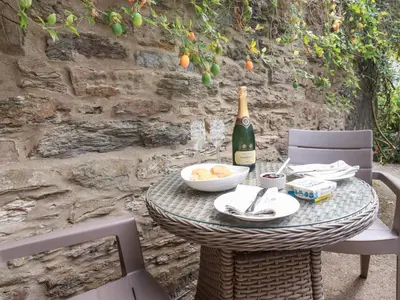 a table with a bottle of wine and a bowl of food at Mithian Cottage in St. Agnes