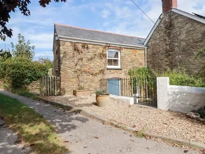 a stone house with a fence in front of it at Mithian Cottage in St. Agnes