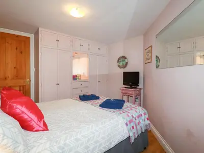 a bedroom with a bed with red pillows on it at Mithian Cottage in St. Agnes