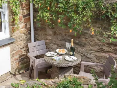 a table and chairs with a bottle of wine on it at Mithian Cottage in St. Agnes