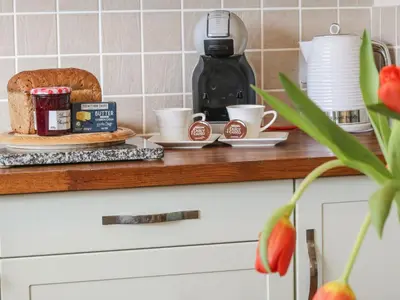 a counter with a plate of bread and coffee cups at Honeysuckle Cottage in Helston
