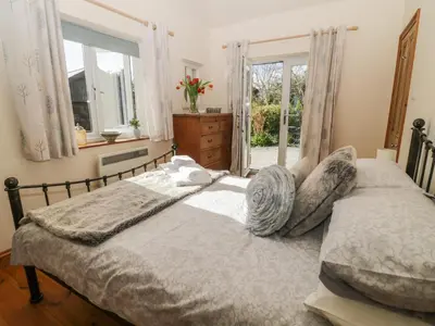 a bedroom with a bed and a window at Honeysuckle Cottage in Helston