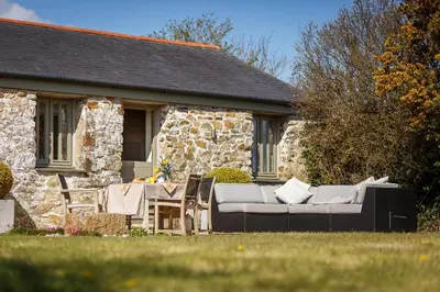 a house with a couch and chairs in front of it at The Granary at Cornish Barn Holidays in Truro
