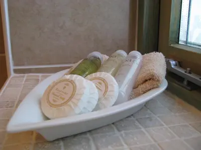 a tray with four bottles of shampoo and seashells at The Granary at Cornish Barn Holidays in Truro