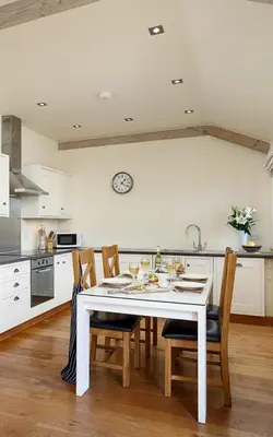 a kitchen with a white table and chairs in a kitchen at The Granary at Cornish Barn Holidays in Truro
