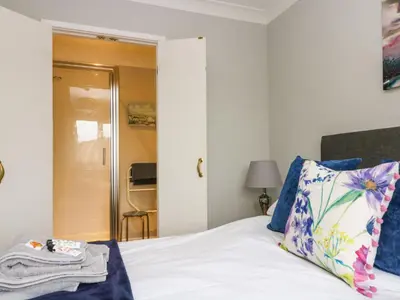 a bedroom with a bed with a blue and white pillow at Heather's Cottage in Budock Water