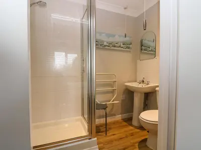 a bathroom with a shower and a toilet and a sink at Heather's Cottage in Budock Water