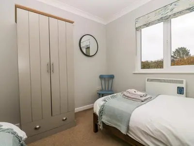 a bedroom with a bed and a mirror and a window at Heather's Cottage in Budock Water