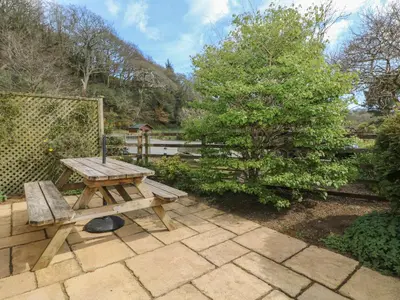 a wooden picnic table sitting on a patio at Heather's Cottage in Budock Water