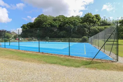 a tennis court with a net on top of it at Heather's Cottage in Budock Water