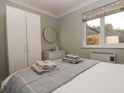a bedroom with a bed with towels on it at Heather's Cottage in Budock Water