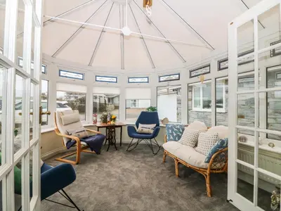 a conservatory with chairs and a table and windows at Bethany Bay View in Cubert