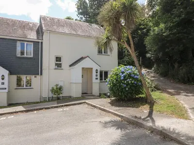 a white house with a palm tree in front of it at Bramble Cottage in Falmouth