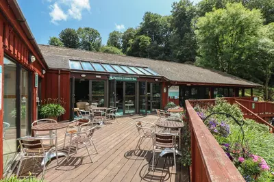 a wooden deck with chairs and tables on a building at Bramble Cottage in Falmouth