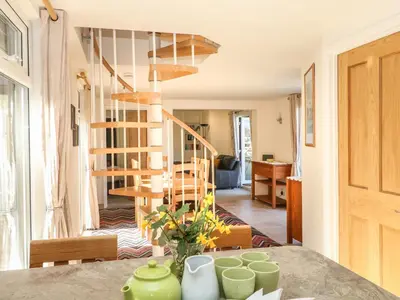 a kitchen and living room with a spiral staircase at Higher Kernick Stable in Bodmin