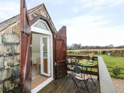 a tiny house with a deck with a table and chairs at Higher Kernick Stable in Bodmin
