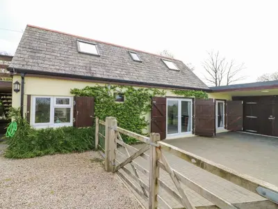a house with a wooden fence and a wooden deck at Higher Kernick Stable in Bodmin