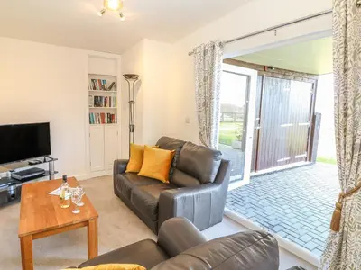 a living room with a leather couch and a tv at Higher Kernick Stable in Bodmin