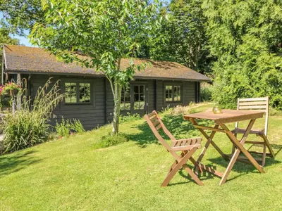 a picnic table and bench in front of a cabin at Pond Cabin in Stithians