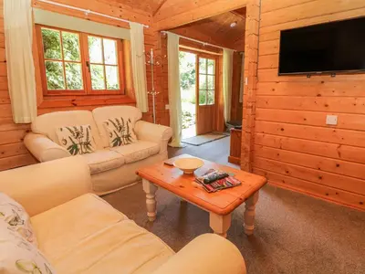 a living room with couches and a tv and a table at Pond Cabin in Stithians