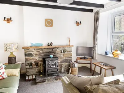a living room with a stone fireplace and a tv at The Old Sweet Shop in Par
