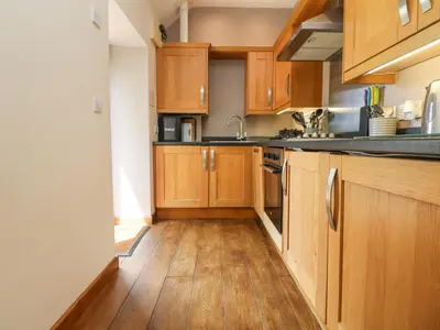 a kitchen with wooden cabinets and a wooden floor at Willow in Falmouth