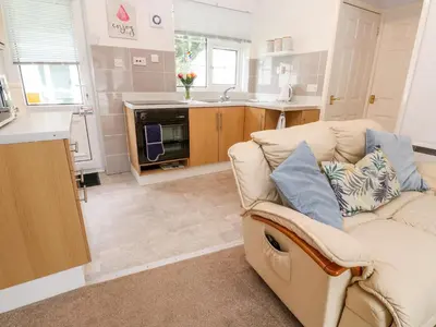a living room with a couch and a kitchen at Brook Haven in Saint Cleer