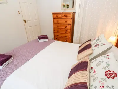 a bedroom with a white bed and a dresser at Brook Haven in Saint Cleer