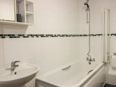 a white bathroom with a sink and a bath tub at 4 Bredon Court in Newquay