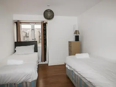 two beds in a room with white walls and a window at 4 Bredon Court in Newquay