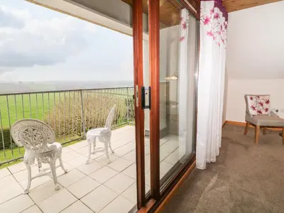 a room with a balcony with chairs and a window at Higher Kernick Farm in Launceston
