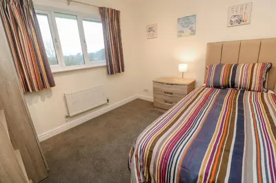 a bedroom with a bed and a dresser and a window at 12 Kel Avon in Truro