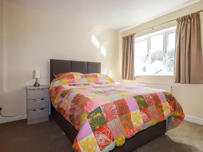 a bedroom with a bed with a colorful comforter and a window at 12 Kel Avon in Truro