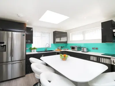 a kitchen with a white table and white chairs at An Drowes in Newquay