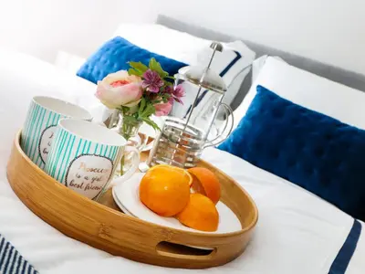 a tray with oranges and cups and flowers on a bed at An Drowes in Newquay