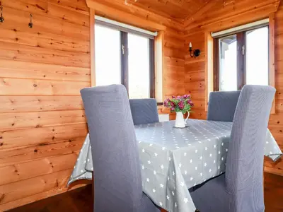 a dining room with a table and chairs with flowers on it at Willow Lodge in Bodmin