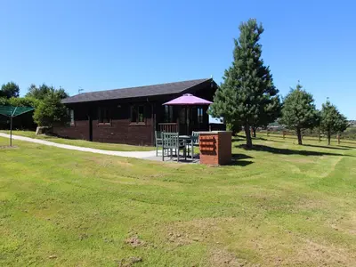 a building with a picnic table in a field at Willow Lodge in Bodmin