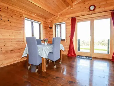 a dining room with a table and blue chairs at Willow Lodge in Bodmin