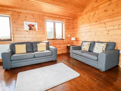 two couches in a living room with wooden walls at Willow Lodge in Bodmin