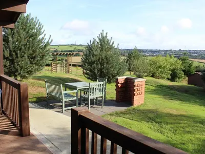 a balcony with a table and chairs on a lawn at Holly Lodge in Bodmin