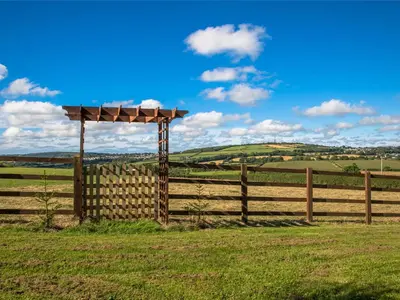 a wooden fence with a pergola in a field at Holly Lodge in Bodmin