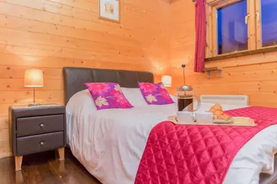 a bedroom with a large bed with pink sheets and a table at Hazel Lodge in Bodmin