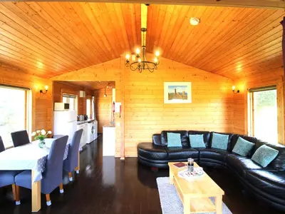 a living room with a black leather couch and a table at Hazel Lodge in Bodmin