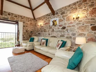 a living room with stone walls and leather couches at Sunnywell in Bodmin
