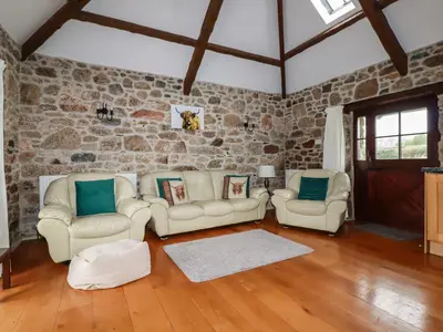 a living room with two white chairs and a stone wall at Sunnywell in Bodmin