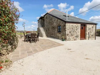 a stone cottage with a table and chairs in front of it at Sunnywell in Bodmin