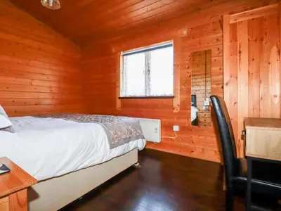 a bedroom with a bed in a wooden cabin at Cherry Lodge in Bodmin
