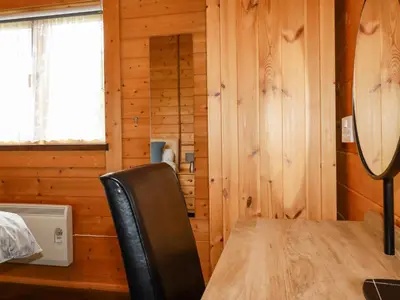 a wooden room with a table and a chair at Cherry Lodge in Bodmin
