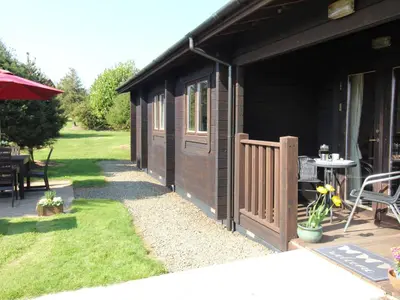 a black building with a wooden door and a patio at Cherry Lodge in Bodmin