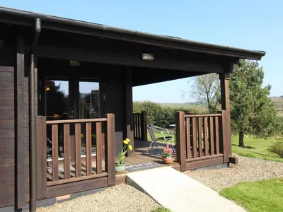 a wooden pavilion with a gate and a patio at Cherry Lodge in Bodmin